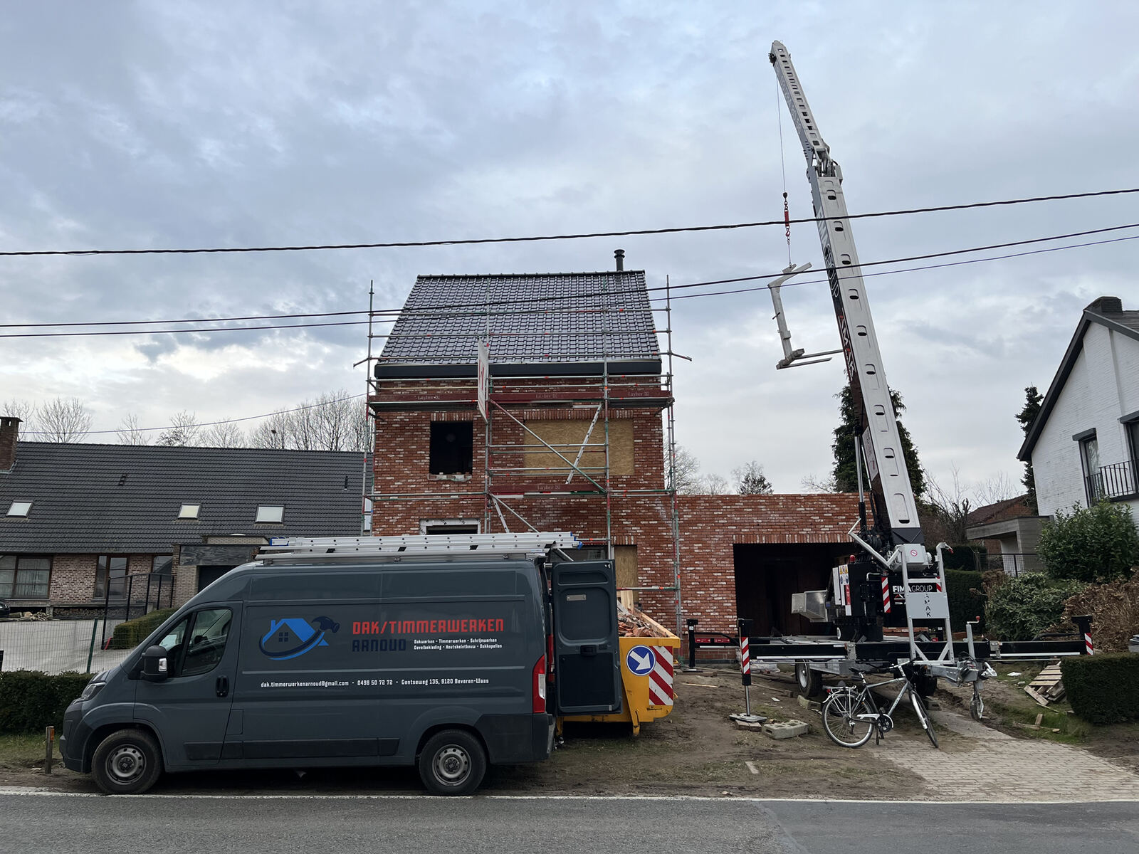 Bestelwagen met kraan levert materiaal op de werf